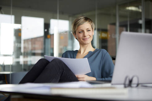 Lächelnde Geschäftsfrau bei der Arbeit am Schreibtisch im Büro - RBF07430