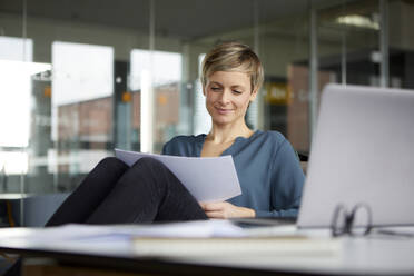 Smiling businesswoman working at desk in office - RBF07431