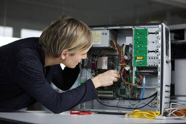 Frau beim Zusammenbau eines Desktop-PCs im Büro - RBF07449