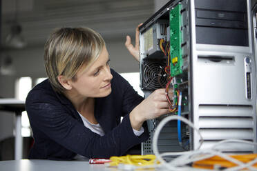 Frau beim Zusammenbau eines Desktop-PCs im Büro - RBF07450