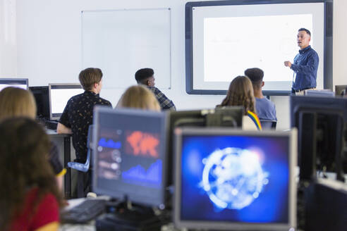 Schüler der Mittelstufe an Computern, die den Lehrer auf der Projektionsfläche im Klassenzimmer beobachten - CAIF25719