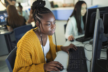 Fokussierte Schülerin der Junior High School bei der Benutzung eines Computers im Computerraum - CAIF25735