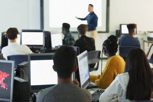 Schüler der Mittelstufe an Computern, die den Lehrer auf der Projektionsfläche im Klassenzimmer beobachten - CAIF25761