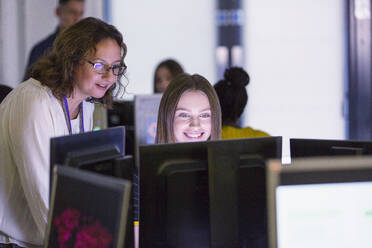 Female junior high teacher helping girl student at computer in computer lab - CAIF25763