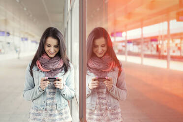 Junge Frau benutzt Smartphone im Bahnhof - CAIF25768