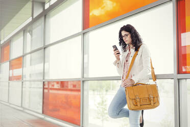 Junge Frau benutzt Smartphone am Bahnhof - CAIF25775