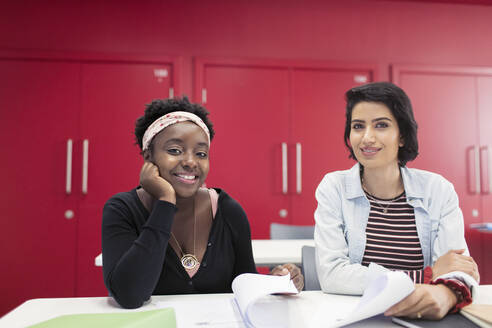 Porträt selbstbewusster, lächelnder weiblicher Community-College-Studenten mit Papierkram im Klassenzimmer - CAIF25801