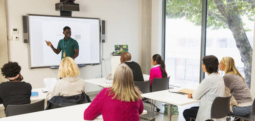 Studenten einer Volkshochschule beobachten den Unterricht ihres Lehrers auf der Projektionsfläche im Klassenzimmer - CAIF25837