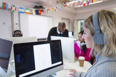Studentin einer Volkshochschule mit Kopfhörern, die einen Computer im Computerlabor benutzt - CAIF25839
