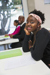 Porträt einer lächelnden, selbstbewussten Studentin einer Volkshochschule im Klassenzimmer - CAIF25914