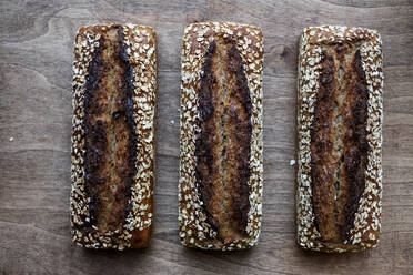 Großaufnahme von drei frisch gebackenen Broten mit Samen in einer handwerklichen Bäckerei. - MINF14539
