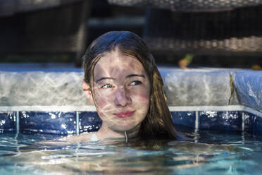 Ein dreizehnjähriges Teenager-Mädchen in einem Schwimmbad mit Lichtreflexen auf ihrem Gesicht - MINF14547