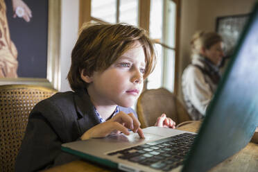 A six year old boy typing on a laptop at home - MINF14559