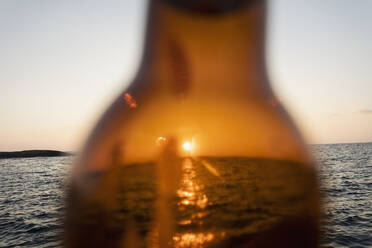 Sonnenuntergang über dem Meer durch braunes Glas Bierflasche - FSIF04615