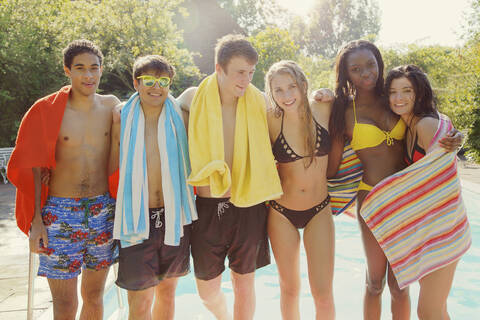 Porträt glückliche Teenager-Freunde am sonnigen Sommerpool, lizenzfreies Stockfoto