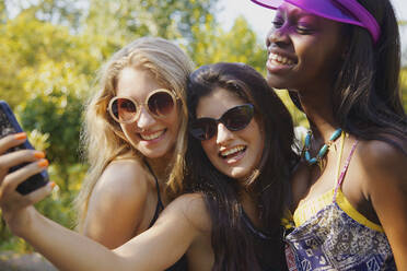 Glückliche Teenager-Freundinnen nehmen Selfie mit Smartphone auf sonnigen Terrasse - FSIF04667