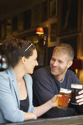 Glückliches Paar trinkt Bier in einer Kneipe - FSIF04690