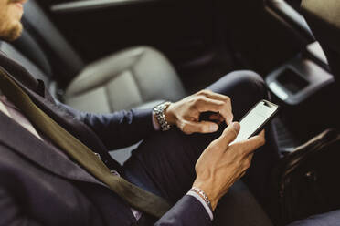 Midsection of businessman using device screen while sitting in car - MASF17611