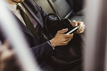 Midsection of businessman using smart phone while sitting in car - MASF17613