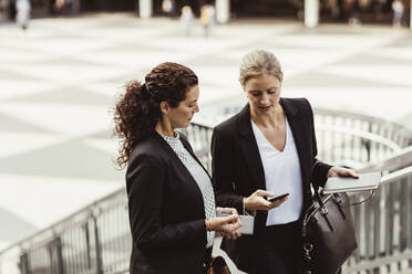 Geschäftsfrau zeigt einer Kollegin ihr Smartphone, während sie im Freien steht - MASF17655