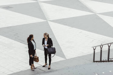 High angle view of female entrepreneurs discussing while standing by staircase - MASF17656