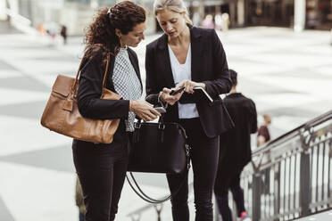 Geschäftsfrau zeigt einer Kollegin ihr Smartphone, während sie im Freien steht - MASF17658
