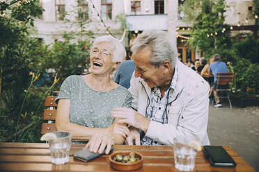 Smiling senior couple tourist sitting at restaurant in city - MASF17676