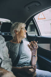 Ältere Frau hält Smartphone im Auto sitzend im Urlaub - MASF17686