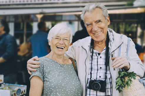 Porträt eines lächelnden älteren Paares, das auf einem Markt in der Stadt steht - MASF17691