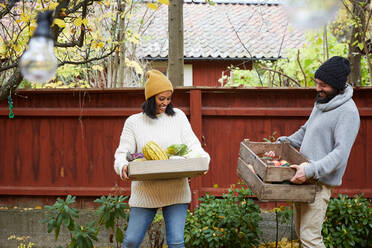 Lächelnder Mann und Frau stehen mit frischem Gemüsekorb im Hof - MASF17722
