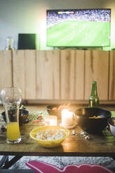 Food and drink on table against TV at living room - MASF17802