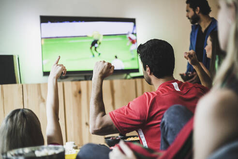Männliche und weibliche Freunde sehen sich zu Hause ein Fußballspiel im Fernsehen an - MASF17828