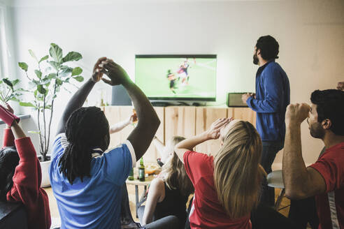 Fans jubeln, während sie ein Fußballspiel zu Hause im Fernsehen verfolgen - MASF17832