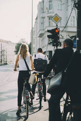 Rückansicht eines Geschäftskollegen, der auf einer Straße in der Stadt Fahrrad fährt - MASF17857