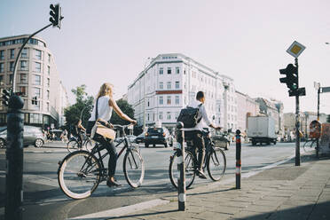 Männliche und weibliche Unternehmer in voller Länge beim Fahrradfahren auf der Straße in der Stadt - MASF17858