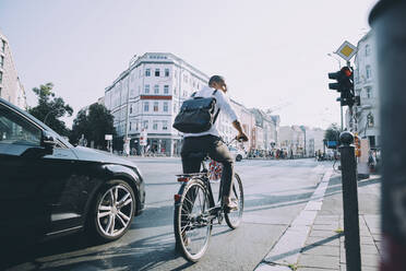 Full length of male entrepreneur riding bicycle on road in city against sky - MASF17861