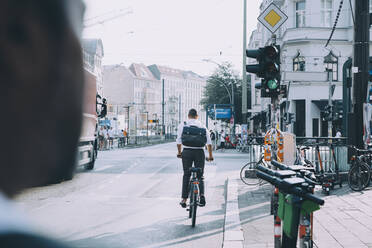 Geschäftsmann mit Rucksack auf dem Fahrrad in voller Länge auf der Straße in der Stadt - MASF17862