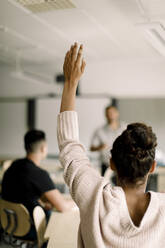 Studentin mit erhobener Hand, während der Tutor im Klassenzimmer steht - MASF17876