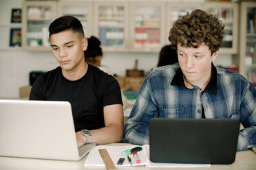 Männliche Schüler benutzen einen Laptop über dem Tisch, während sie im Klassenzimmer sitzen - MASF17891