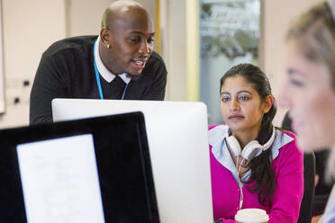 Community college instructor helping student at computer in classroom - CAIF25917