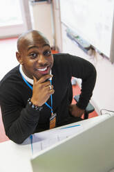 Portrait confident, smiling male community college instructor at computer in classroom - CAIF25918