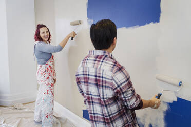 Happy couple painting wall - CAIF25955