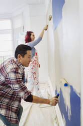 Couple painting wall with paint rollers - CAIF25966