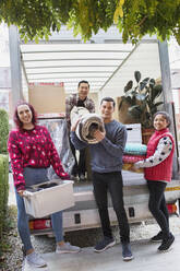 Portrait happy friends unloading belongings from moving van - CAIF25979