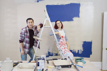 Portrait couple redecorating, painting wall - CAIF25982