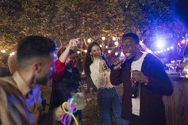 Freunde tanzen und singen Karaoke auf einer Gartenparty - CAIF26007