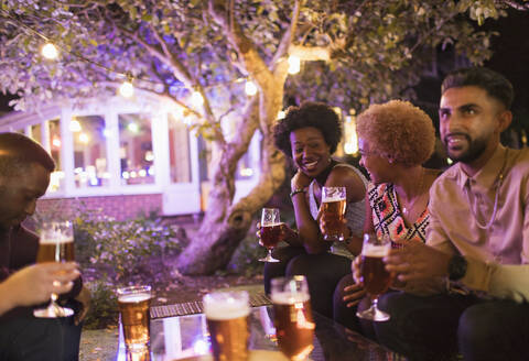 Freunde unterhalten sich und trinken Bier auf einer Gartenparty, lizenzfreies Stockfoto