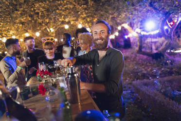 Porträt glücklicher Mann, der für Freunde bei einer Gartenparty kellnert - CAIF26030