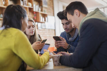 Young adult friends using smart phones at cafe table - CAIF26038