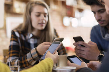 Young adult friends using smart phones in cafe - CAIF26048